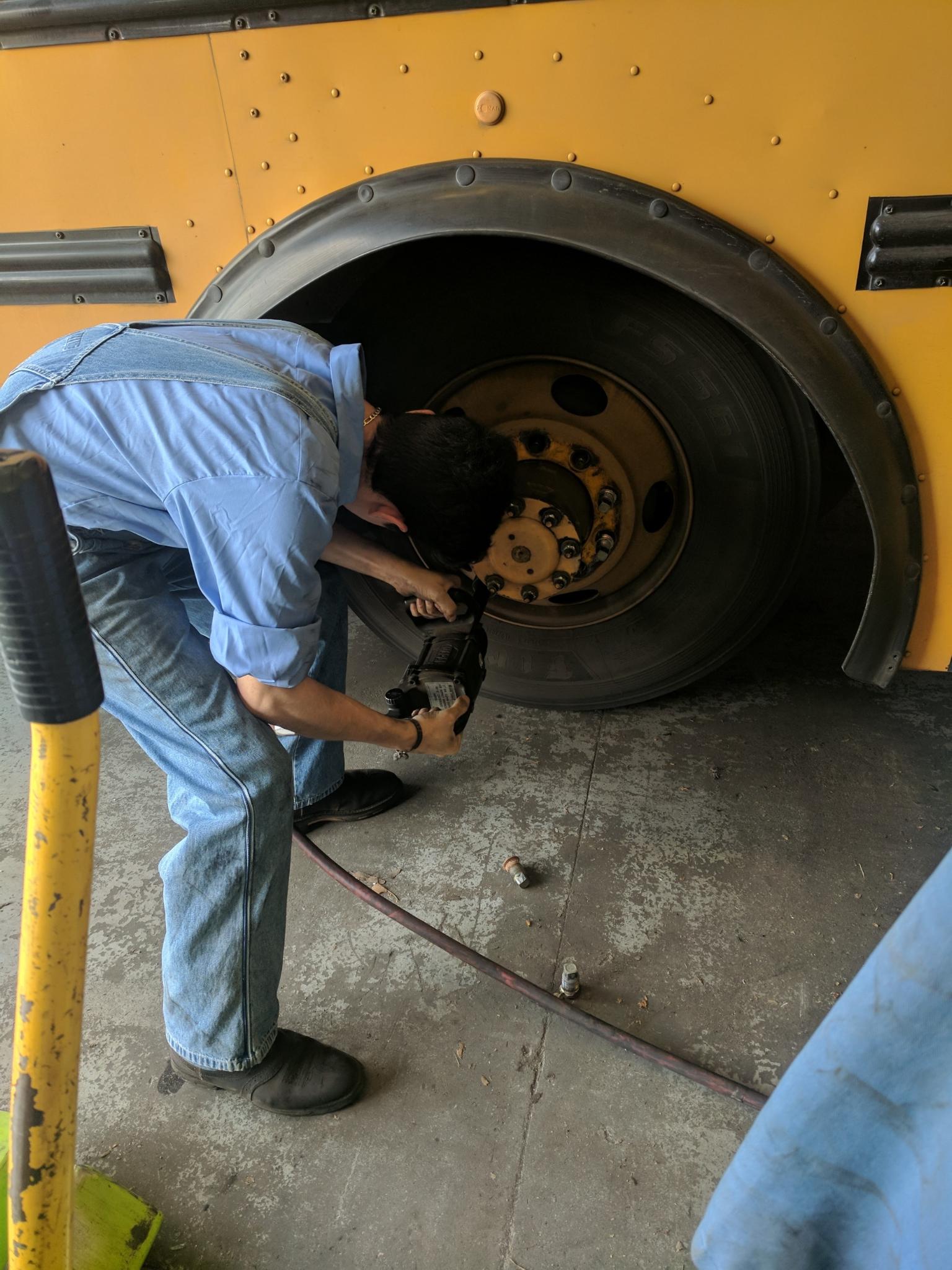 Daniel Loza working on tire of JUSD bus