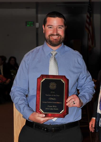 Shane Wells standing with award