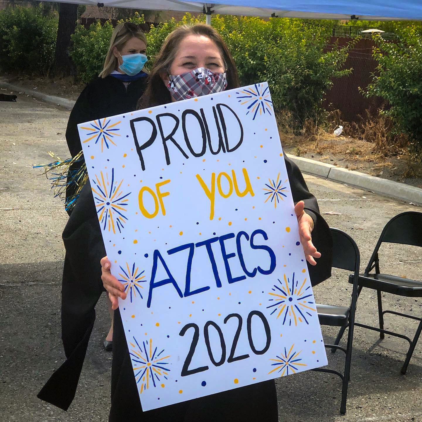 Woman in mask holds sign reading "Proud of you Aztecs 2020"