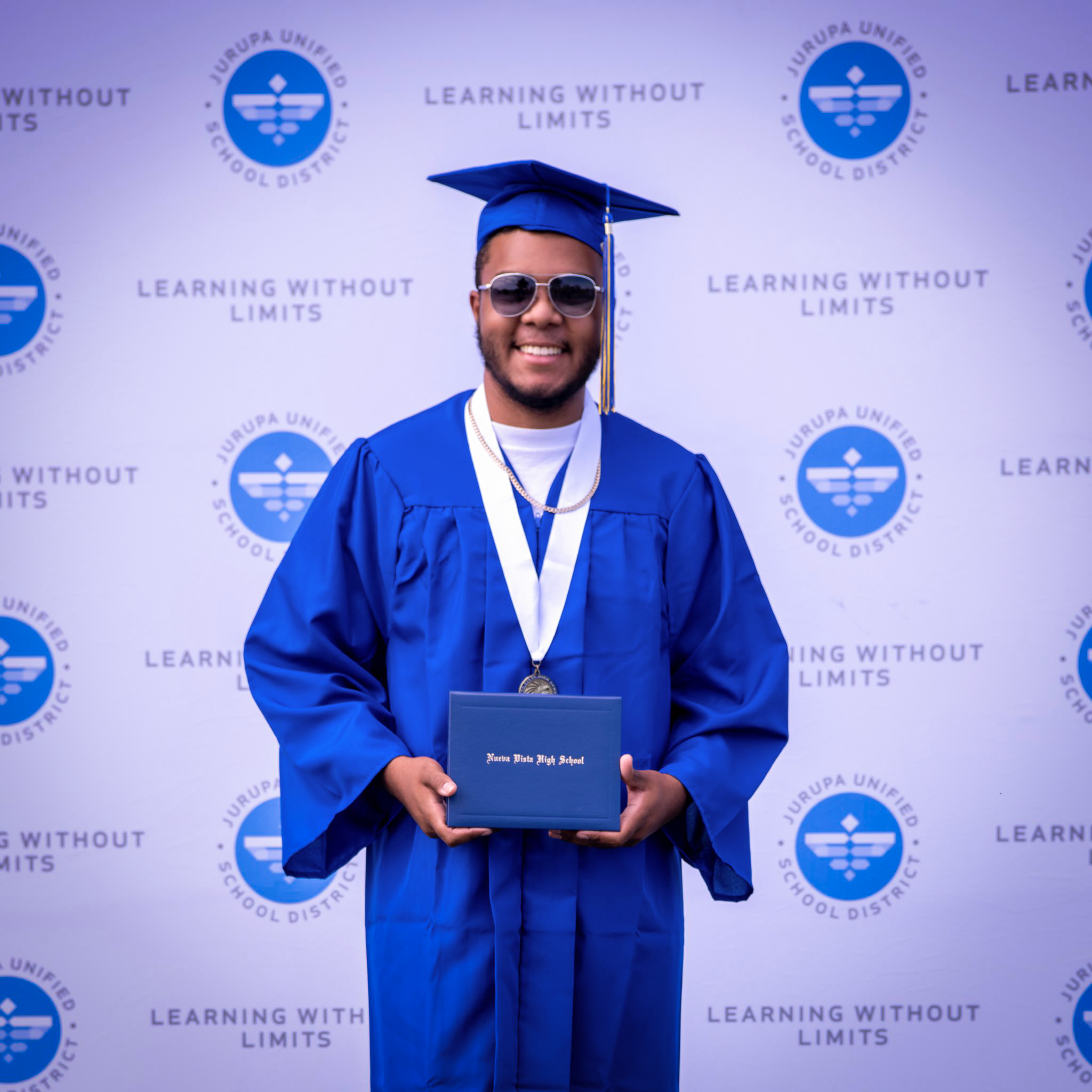 Graduate in sunglasses poses with diploma