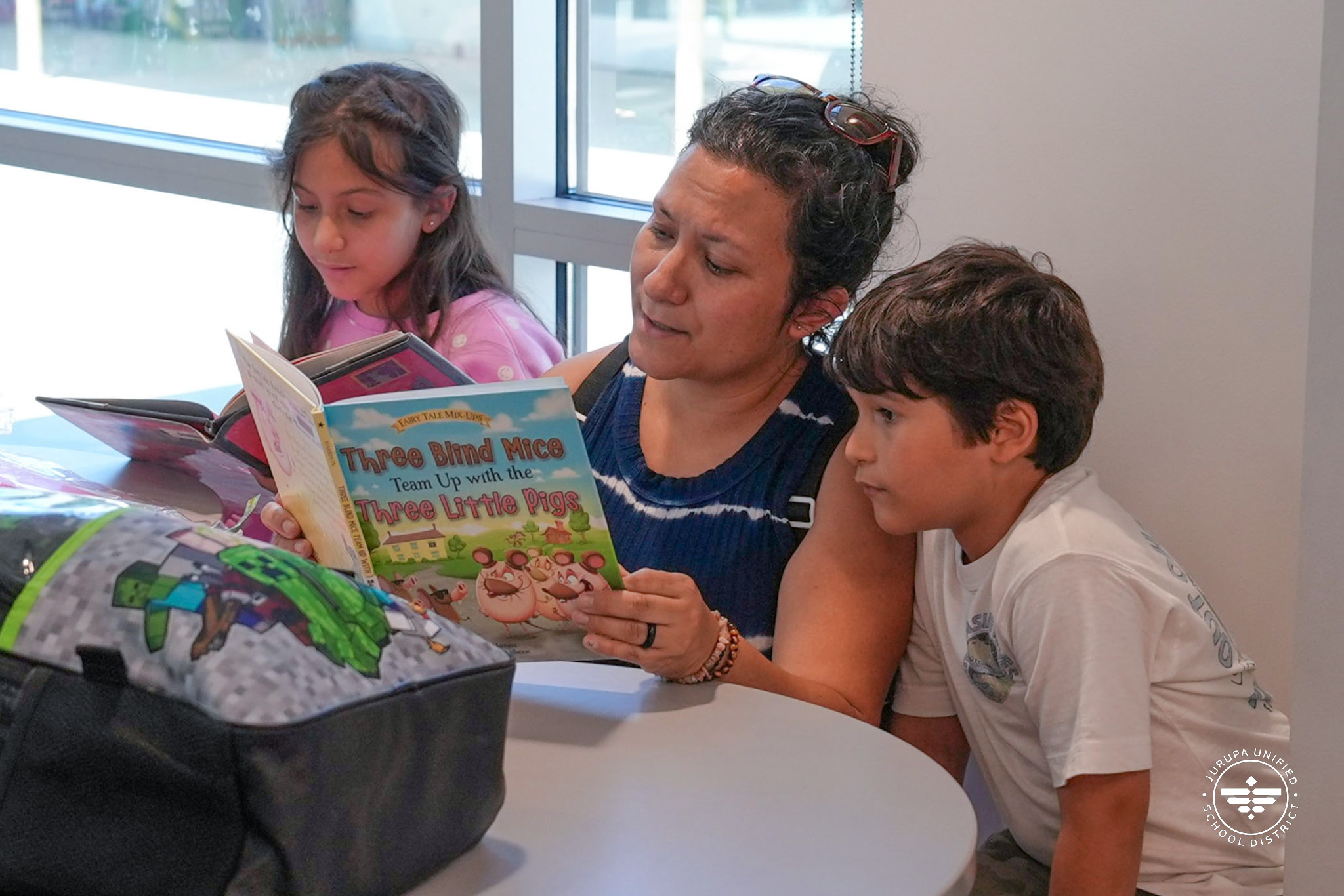 a parent reading with her two children in the library