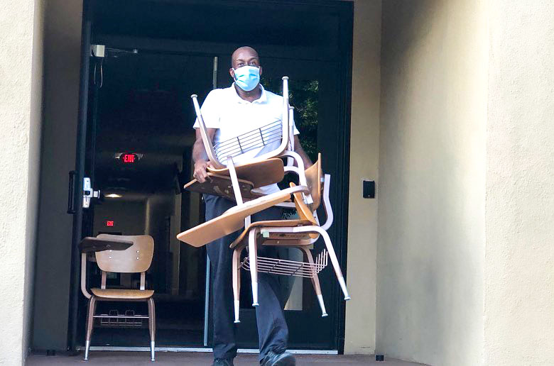 Man in a mask carries desks