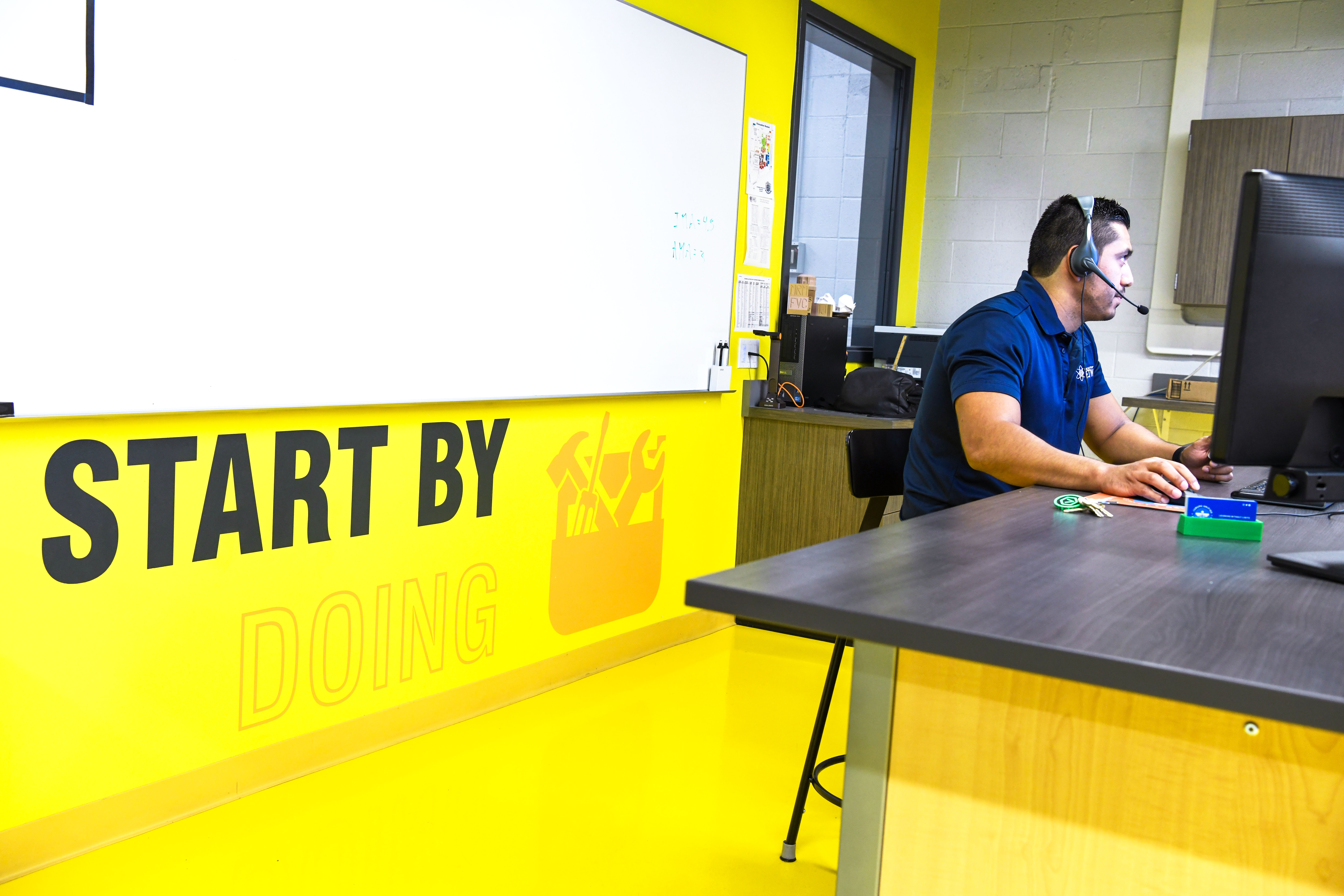 Mr. Cerda teaches online. Behind him is a graphic on the wall that reads "Start by Doing."