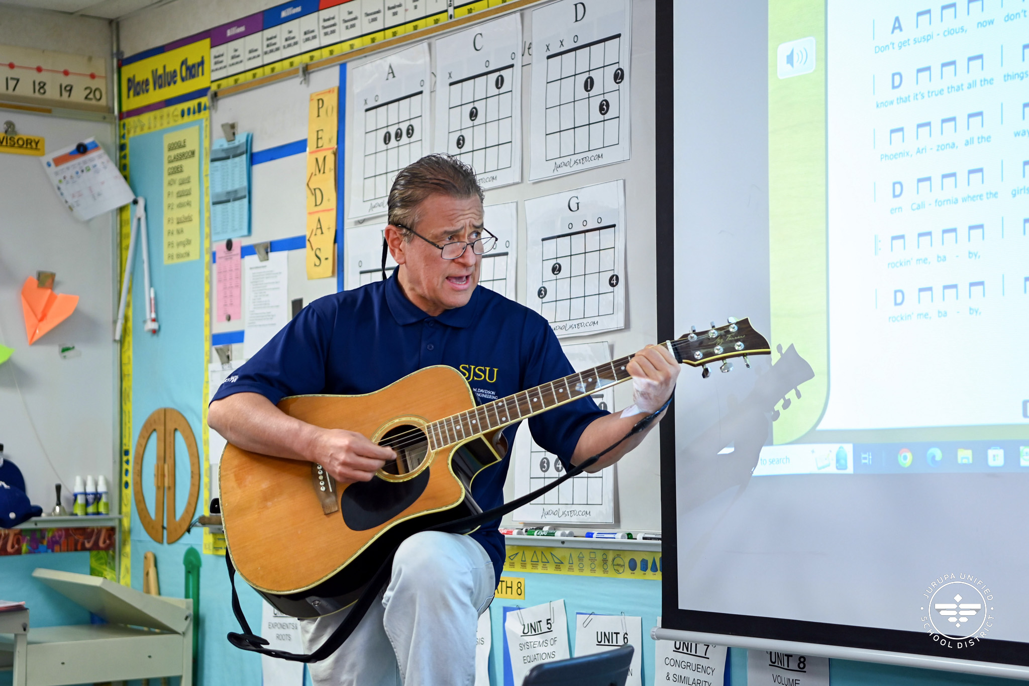 John Parker teaching students as he plays the guitar