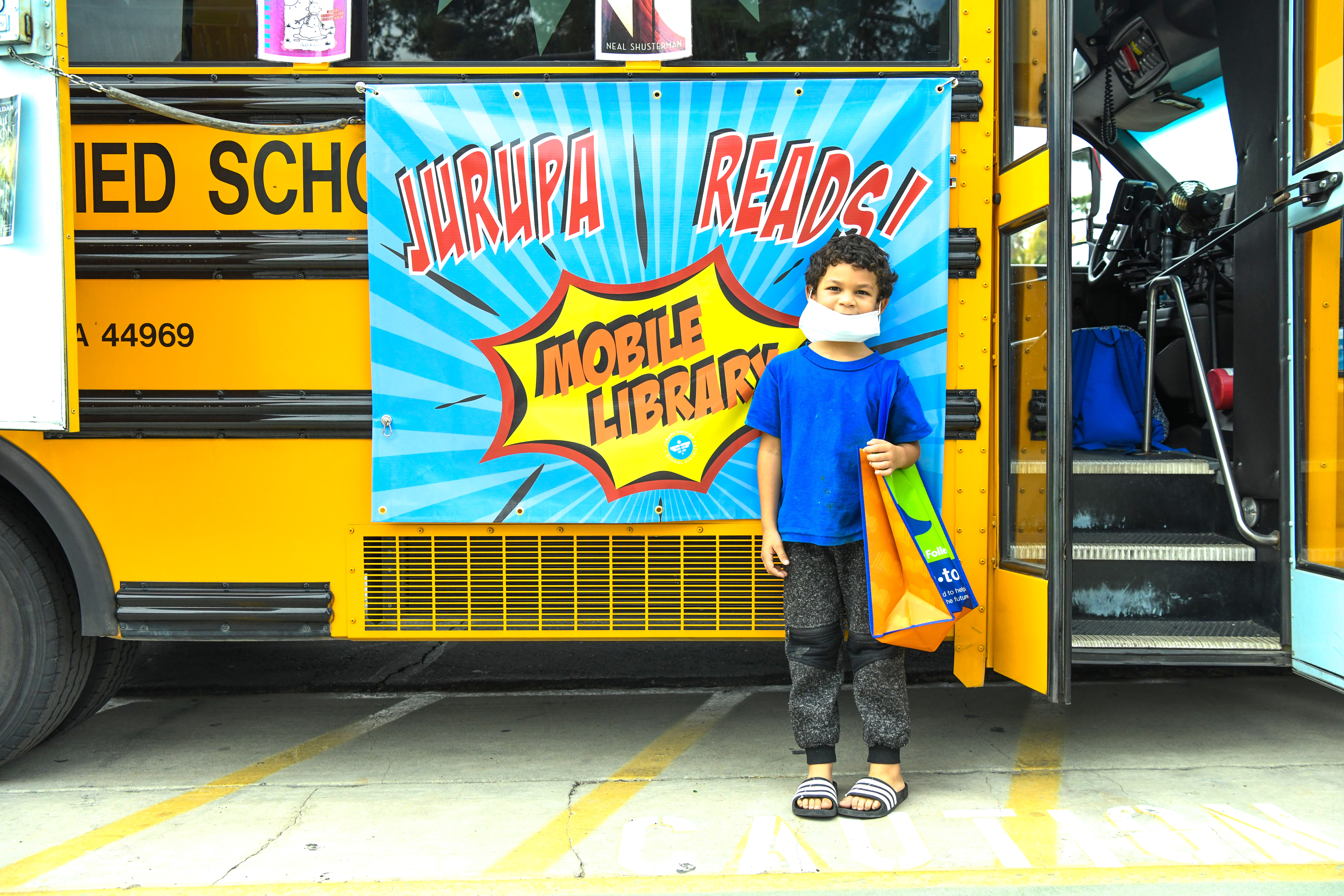 young boy poses in front of mobile library