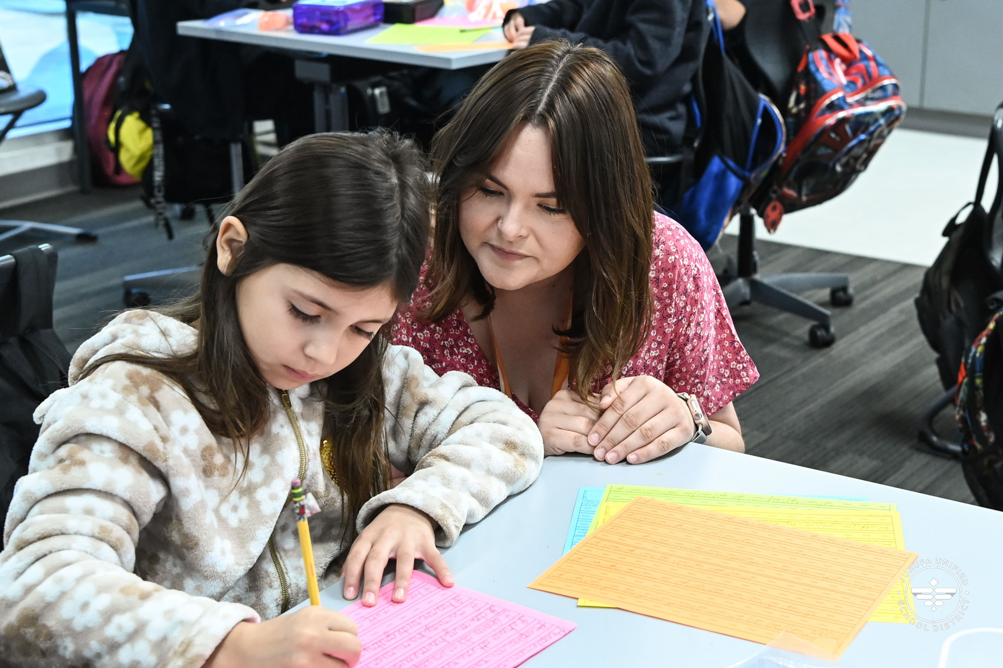 Ms. Horton at a student's desk while they practice their cursive skills